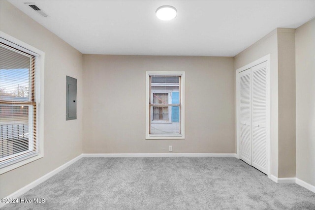 unfurnished bedroom featuring light carpet, electric panel, and a closet