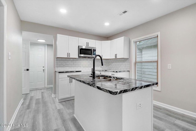 kitchen featuring a kitchen island with sink, sink, white cabinets, and light hardwood / wood-style floors