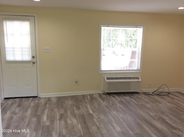 entryway featuring a wall unit AC, wood-type flooring, and a wealth of natural light