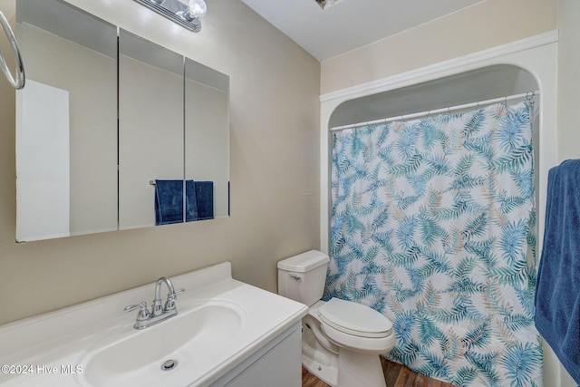 bathroom featuring hardwood / wood-style floors, vanity, toilet, and walk in shower