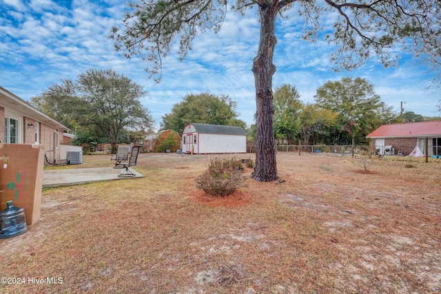 view of yard featuring central AC, a patio area, and a storage shed