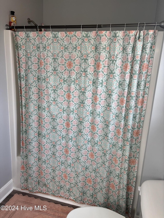 full bath with toilet and a shower with shower curtain