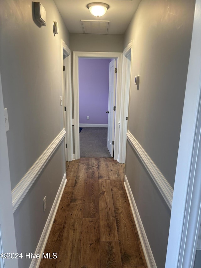 hallway featuring baseboards, attic access, and wood finished floors