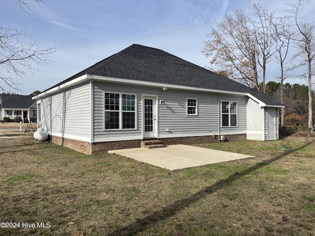 rear view of property featuring a patio, a shingled roof, entry steps, crawl space, and a lawn