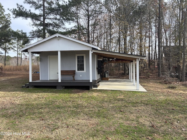 view of front of home with a front lawn, a carport, and an outbuilding