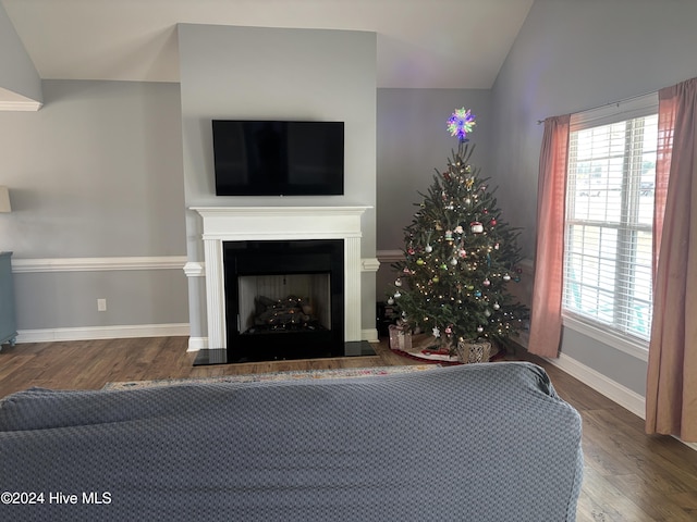 unfurnished living room with vaulted ceiling, wood finished floors, a fireplace, and baseboards