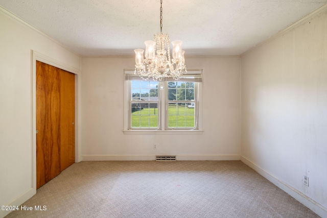 carpeted empty room with ornamental molding, a chandelier, and a textured ceiling