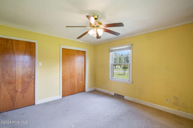 unfurnished bedroom with ceiling fan, ornamental molding, and light carpet