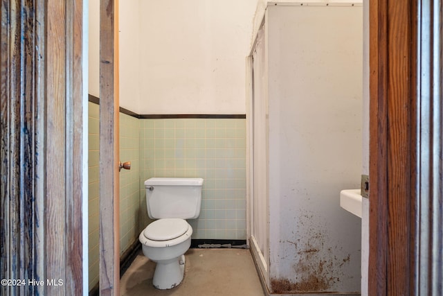 bathroom featuring toilet and tile walls