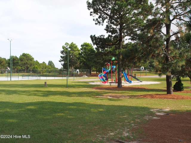 view of community featuring a playground, a lawn, and tennis court