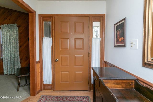 foyer with light hardwood / wood-style floors and wooden walls