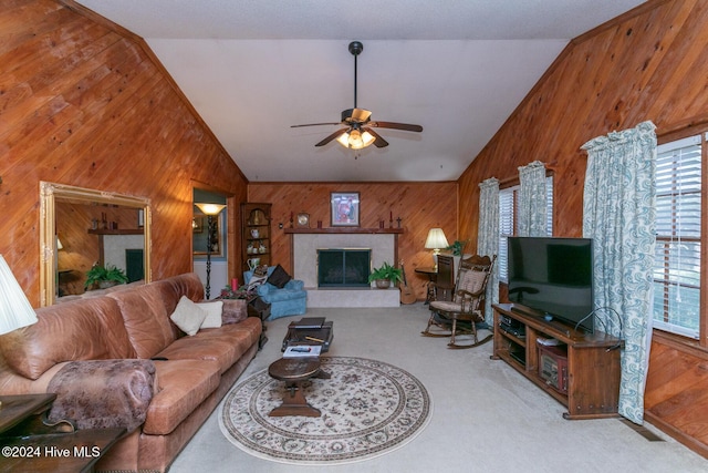 carpeted living room featuring ceiling fan, wood walls, and lofted ceiling