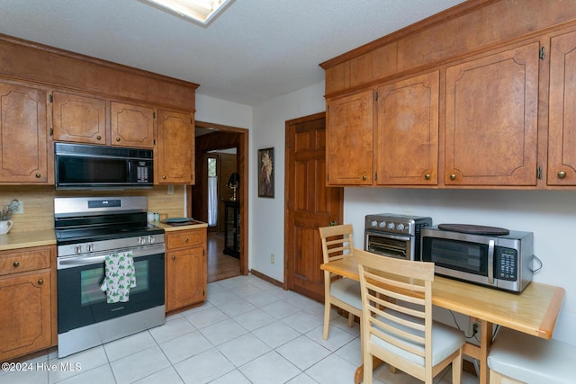 kitchen with appliances with stainless steel finishes, tasteful backsplash, and light tile patterned floors