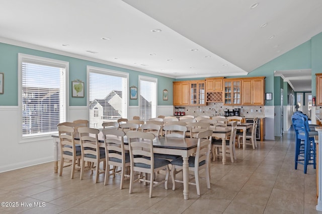 dining room with ornamental molding, light tile patterned flooring, and lofted ceiling