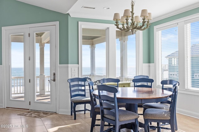 dining room with a notable chandelier, a water view, light tile patterned floors, and crown molding