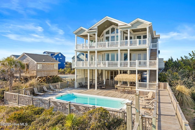 rear view of property with a patio, a balcony, and a community pool