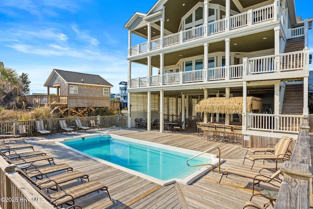 view of swimming pool featuring a wooden deck and a bar