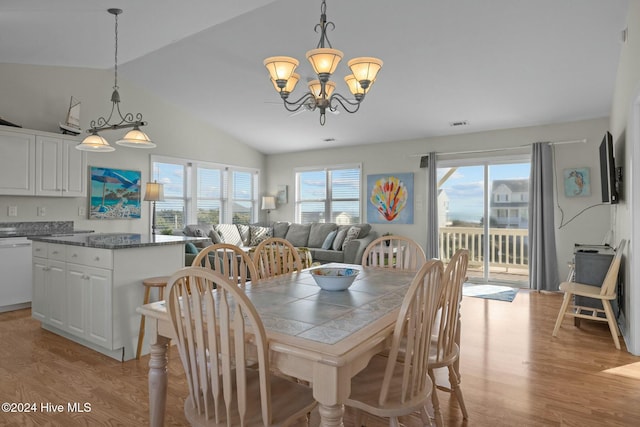 dining area with vaulted ceiling, a healthy amount of sunlight, light wood-type flooring, and a chandelier