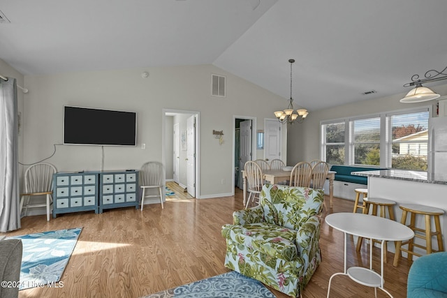 living room featuring a notable chandelier, lofted ceiling, and light hardwood / wood-style flooring