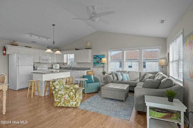 living room featuring ceiling fan, sink, rail lighting, lofted ceiling, and light wood-type flooring