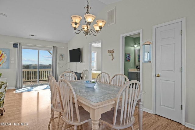 dining space featuring light hardwood / wood-style flooring, lofted ceiling, and a notable chandelier