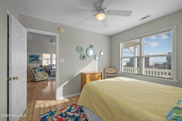 bedroom featuring hardwood / wood-style floors, ceiling fan, lofted ceiling, and multiple windows