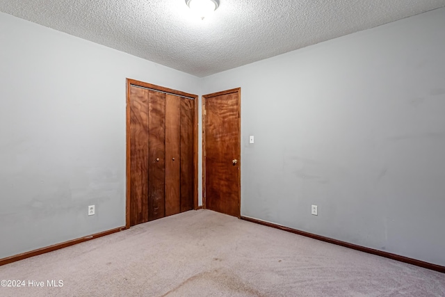 unfurnished bedroom with carpet, a textured ceiling, and a closet