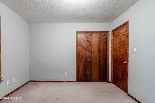 unfurnished bedroom featuring a closet, light colored carpet, and a textured ceiling