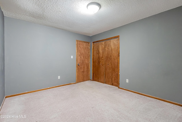 unfurnished bedroom featuring carpet flooring, a closet, and a textured ceiling