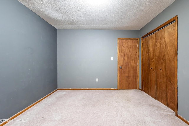 unfurnished bedroom with carpet flooring, a textured ceiling, and a closet