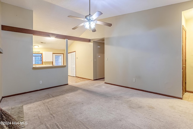 spare room with ceiling fan, lofted ceiling, and light carpet