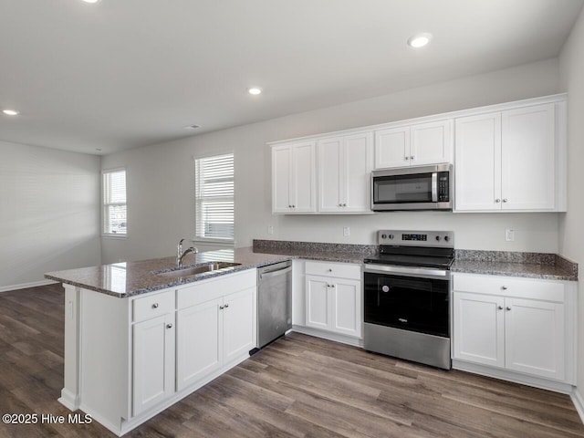 kitchen with a peninsula, white cabinetry, appliances with stainless steel finishes, and a sink