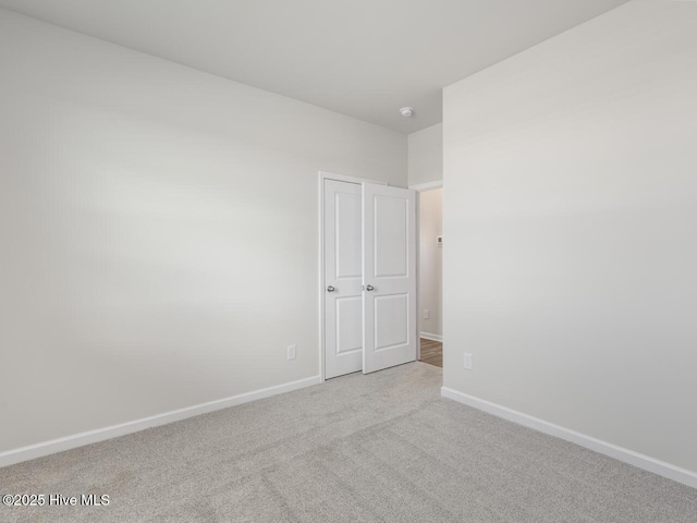 unfurnished room with baseboards and light colored carpet