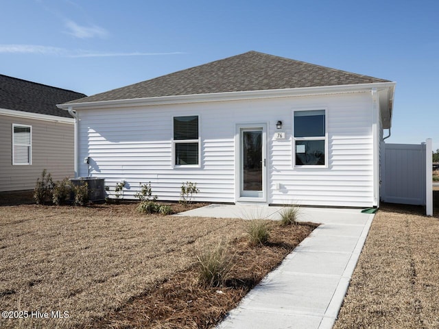 rear view of property featuring a patio area, a yard, a shingled roof, and central AC unit