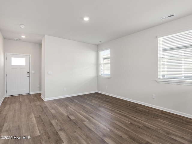 spare room with dark wood-style flooring, recessed lighting, visible vents, and baseboards