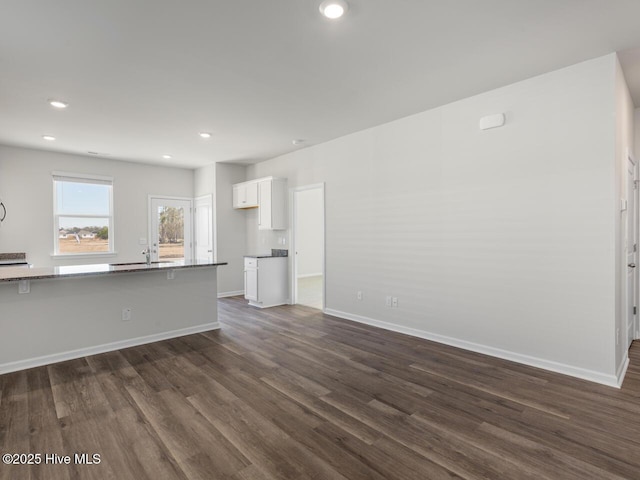 unfurnished living room featuring dark wood-type flooring, recessed lighting, a sink, and baseboards