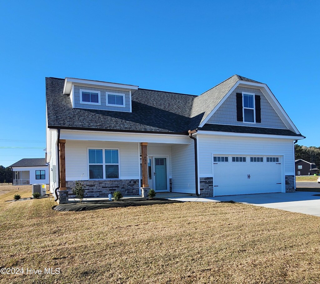 craftsman-style house featuring a porch, cooling unit, a garage, and a front yard