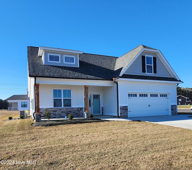 craftsman-style house featuring a porch, cooling unit, a garage, and a front yard