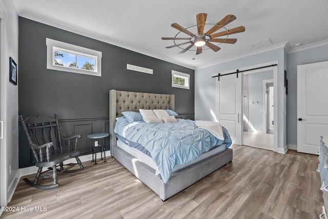 bedroom with crown molding, hardwood / wood-style flooring, a barn door, and ceiling fan