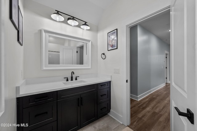 bathroom featuring vanity, wood-type flooring, and lofted ceiling