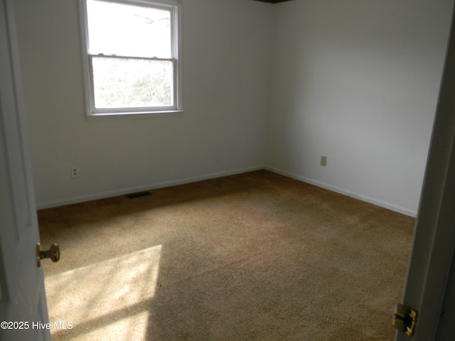 carpeted spare room featuring visible vents and baseboards