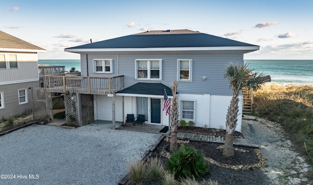 view of front of home with a deck with water view and a beach view