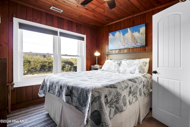 bedroom with ceiling fan, wooden walls, and wooden ceiling