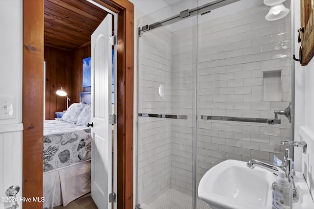 bathroom featuring wooden walls, sink, and a shower with shower door