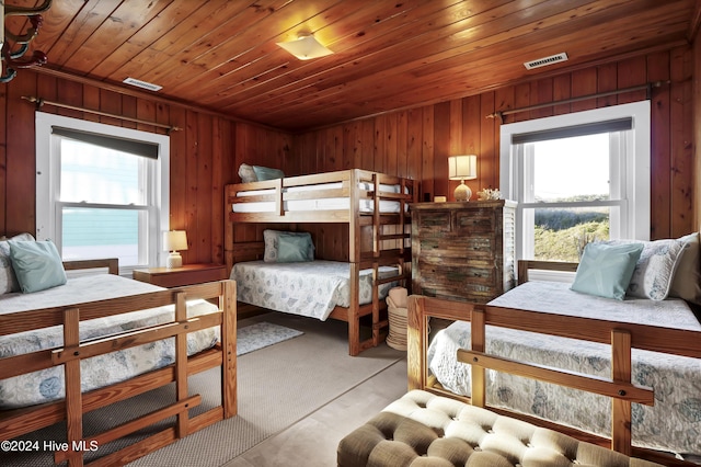 bedroom featuring multiple windows, wooden ceiling, and wood walls