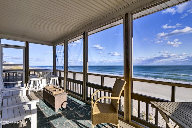 sunroom / solarium with a view of the beach and a water view