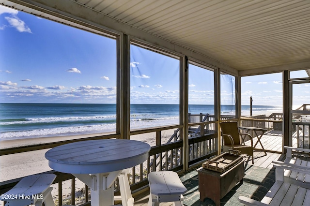 sunroom / solarium featuring a water view and a beach view