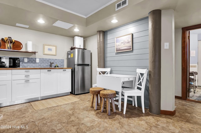 kitchen featuring backsplash, wooden counters, white cabinets, sink, and stainless steel fridge