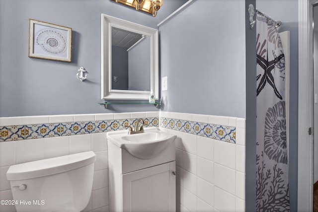 bathroom featuring vanity, toilet, and tile walls