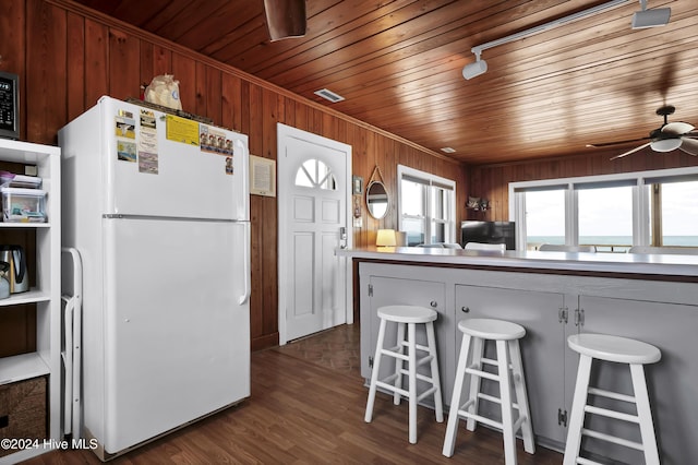 kitchen featuring a breakfast bar, white fridge, wood ceiling, and dark hardwood / wood-style floors